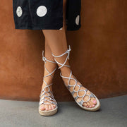 woman's feet in silver and white sandals near brown wall with spot dots on it